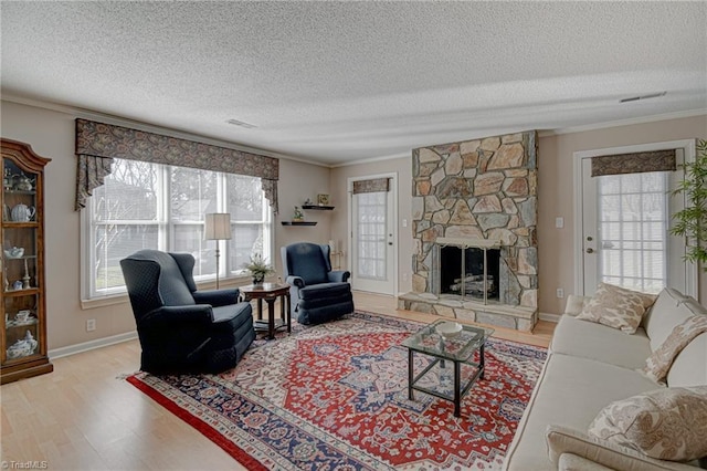 living room featuring hardwood / wood-style flooring, a textured ceiling, ornamental molding, and a fireplace