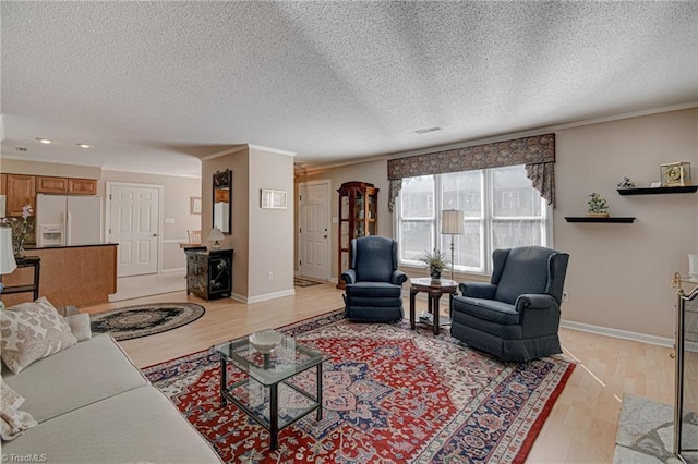 living room with ornamental molding, light hardwood / wood-style floors, and a textured ceiling