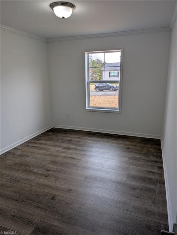 spare room featuring dark wood-type flooring and ornamental molding