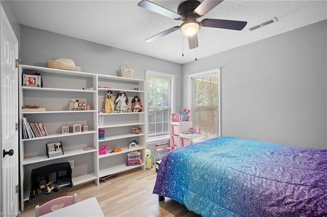 bedroom with wood finished floors, a textured ceiling, and a ceiling fan