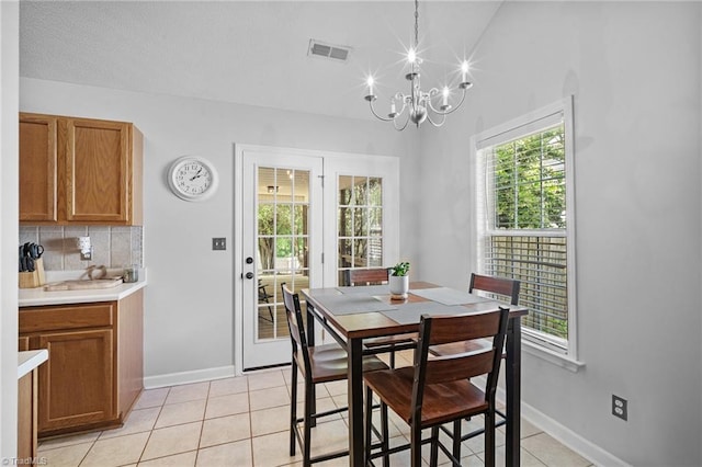 dining area featuring a chandelier, light tile patterned floors, baseboards, and lofted ceiling