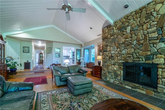 living room with ceiling fan, wood ceiling, a stone fireplace, high vaulted ceiling, and hardwood / wood-style floors