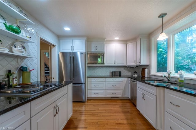 kitchen featuring white cabinets, sink, stainless steel appliances, dark stone countertops, and light wood-type flooring