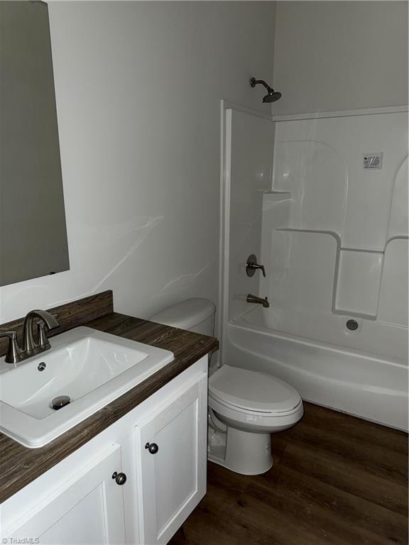 full bathroom featuring vanity, hardwood / wood-style flooring, toilet, and shower / washtub combination