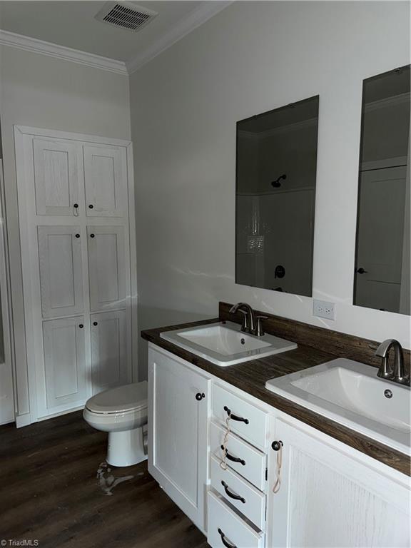 bathroom with hardwood / wood-style floors, vanity, toilet, and crown molding