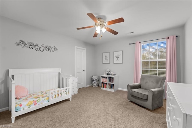 bedroom with ceiling fan, a nursery area, and light carpet