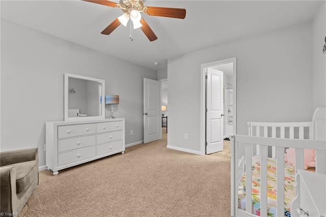 carpeted bedroom with connected bathroom, ceiling fan, and a crib