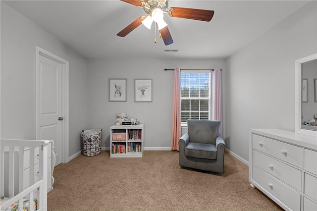 bedroom with light colored carpet, ceiling fan, and a crib