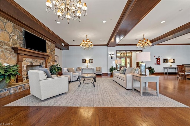 living room with beam ceiling, ornamental molding, a stone fireplace, an inviting chandelier, and light hardwood / wood-style floors