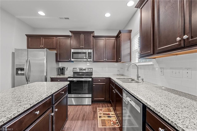 kitchen featuring light stone counters, dark brown cabinetry, sink, appliances with stainless steel finishes, and dark hardwood / wood-style flooring