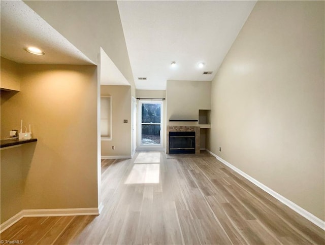 unfurnished living room with wood-type flooring and a tiled fireplace