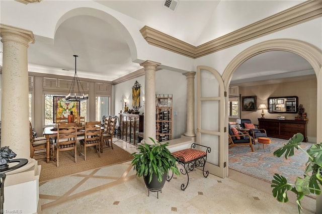 interior space with ornamental molding, a chandelier, and ornate columns