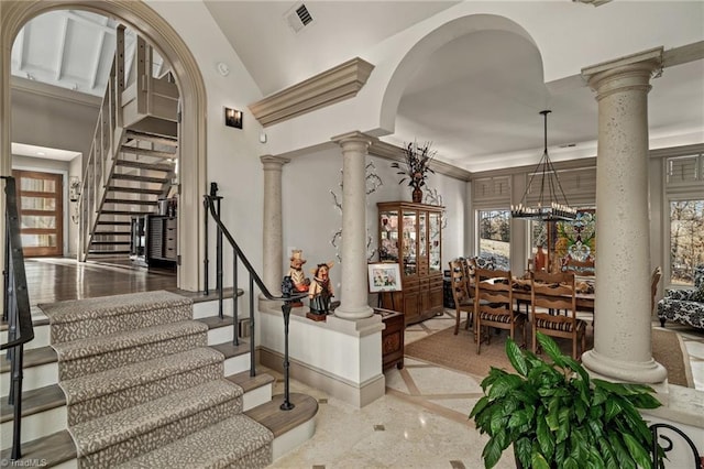 entrance foyer featuring a wealth of natural light, ornate columns, and a notable chandelier