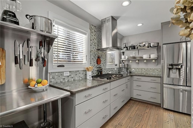 kitchen featuring ventilation hood, appliances with stainless steel finishes, light hardwood / wood-style floors, and a wealth of natural light