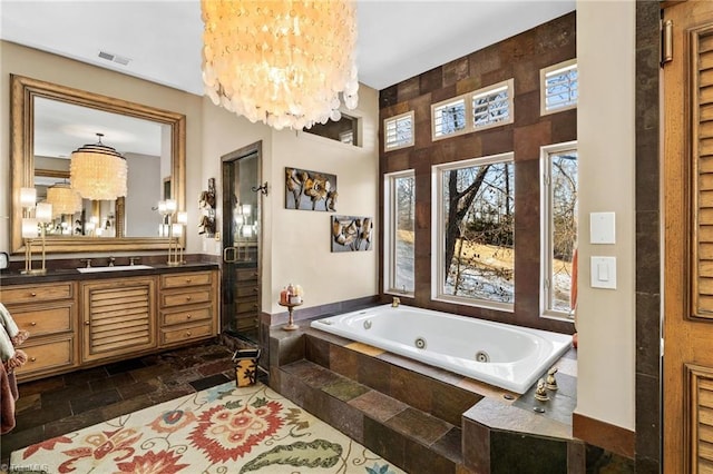 bathroom featuring vanity, a relaxing tiled tub, and a notable chandelier