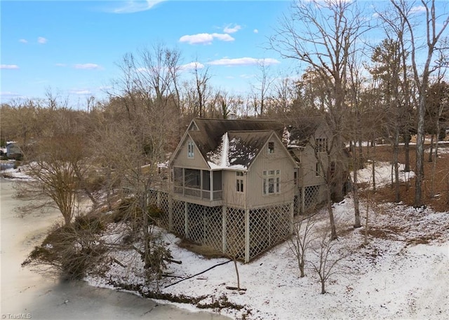 snow covered back of property with a sunroom