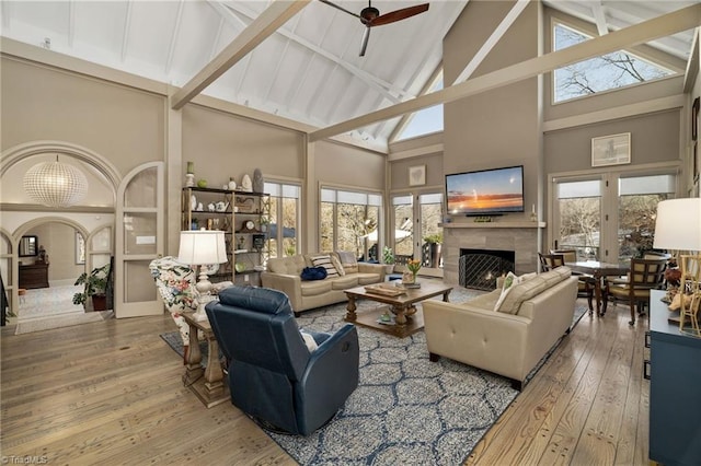 living room with hardwood / wood-style floors, a high end fireplace, ceiling fan, high vaulted ceiling, and beam ceiling