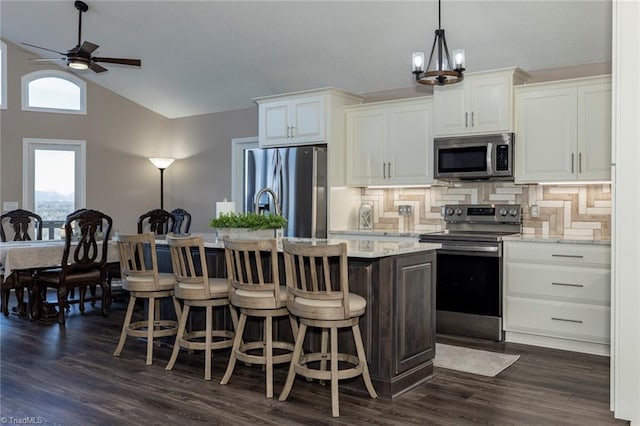 4933 W NC Highway 268, Wilkesboro, NC 28697 - kitchen featuring appliances with stainless steel finishes, tasteful backsplash, an island with sink, white cabinetry, and vaulted ceiling
