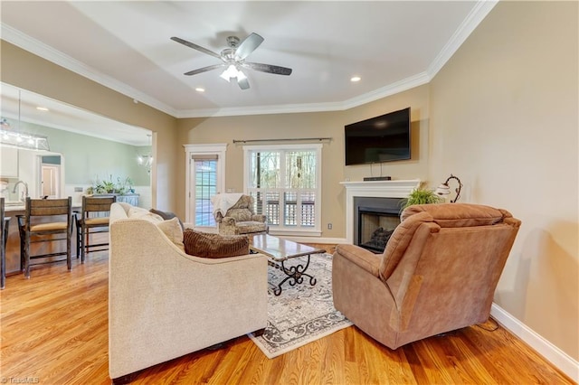 living room with ornamental molding, ceiling fan, and light hardwood / wood-style floors