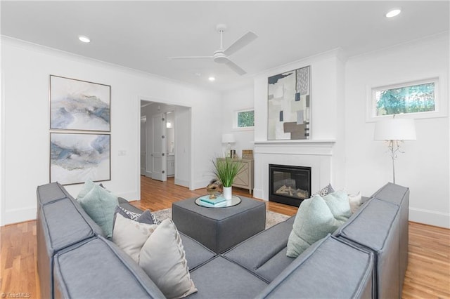 living room featuring light wood finished floors, a glass covered fireplace, recessed lighting, and crown molding