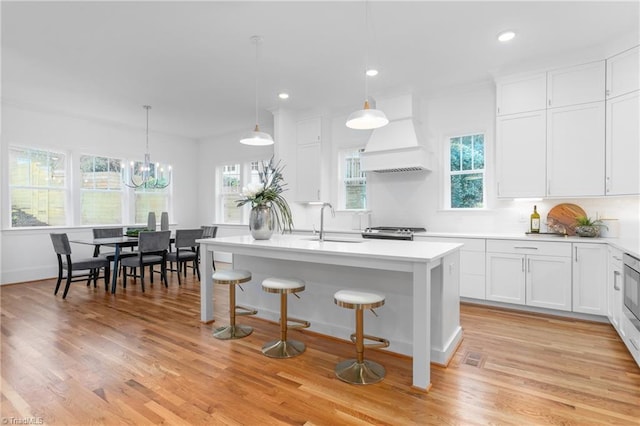 kitchen with custom exhaust hood, a sink, light countertops, stainless steel range oven, and white cabinets