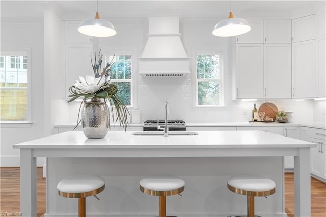 kitchen with backsplash, a kitchen bar, and premium range hood