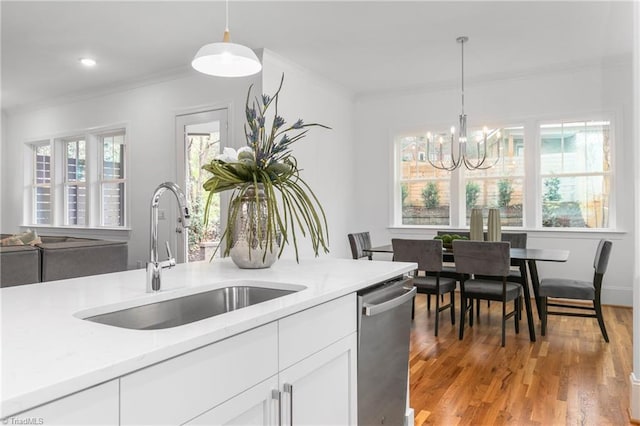 kitchen featuring a sink, stainless steel dishwasher, white cabinets, crown molding, and light wood finished floors