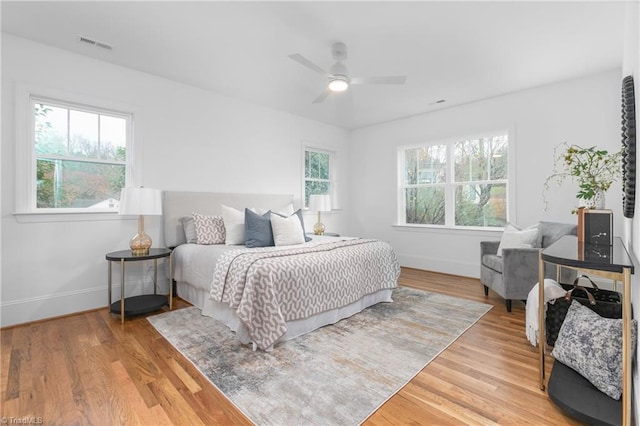 bedroom featuring ceiling fan, visible vents, baseboards, and wood finished floors