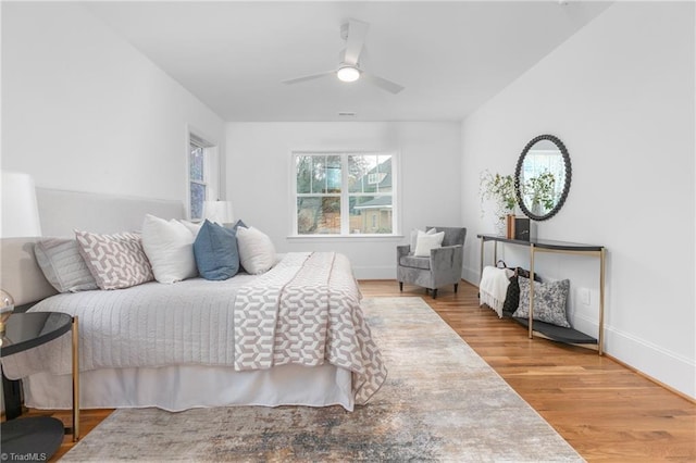 bedroom featuring baseboards, wood finished floors, and a ceiling fan