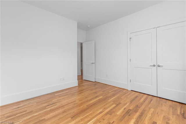 unfurnished bedroom featuring light wood finished floors, a closet, and baseboards