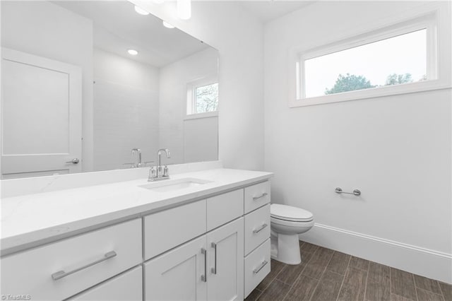 bathroom with vanity, toilet, wood finished floors, and baseboards