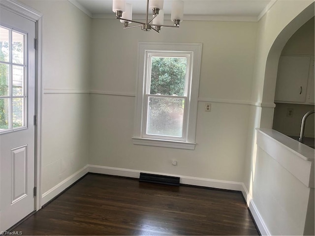 630 Liberty Rd, High Point, NC 27263 - unfurnished dining area featuring arched walkways, dark wood finished floors, ornamental molding, and a chandelier