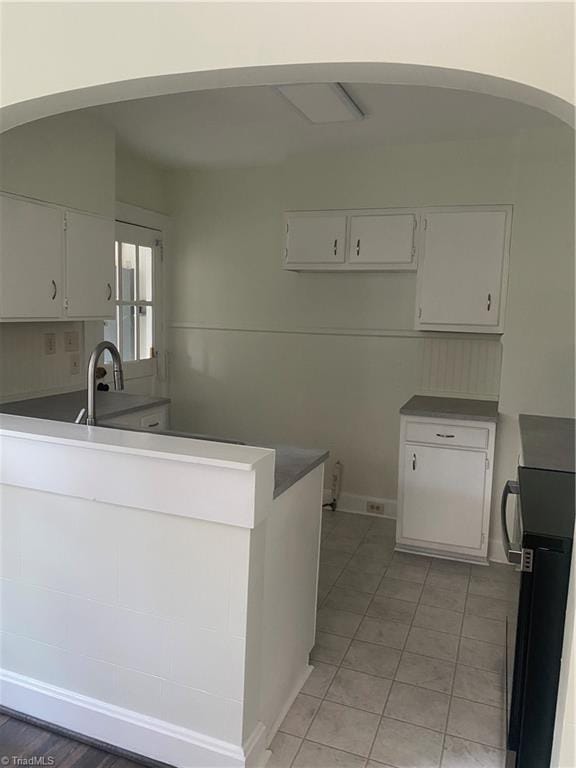 630 Liberty Rd, High Point, NC 27263 - kitchen with white cabinetry, a peninsula, light tile patterned floors, arched walkways, and stove