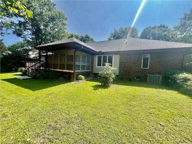 1223 Gatehouse Rd, High Point, NC 27262 - back of property with a sunroom, central AC unit, brick siding, a yard, and roof with shingles