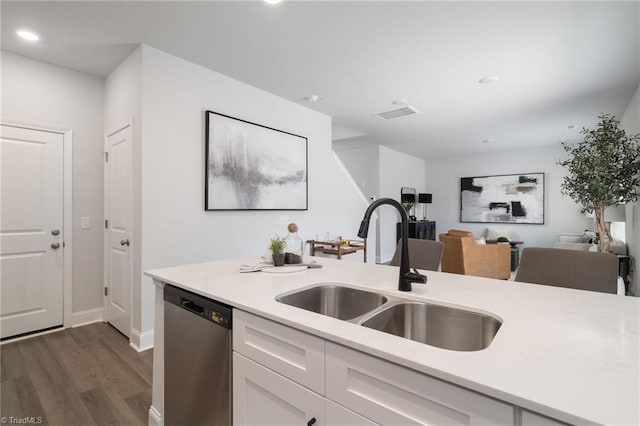 kitchen with dark wood-type flooring, white cabinetry, stainless steel dishwasher, and sink