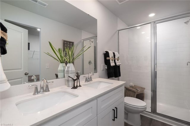 bathroom with hardwood / wood-style flooring, a shower with shower door, vanity, and toilet