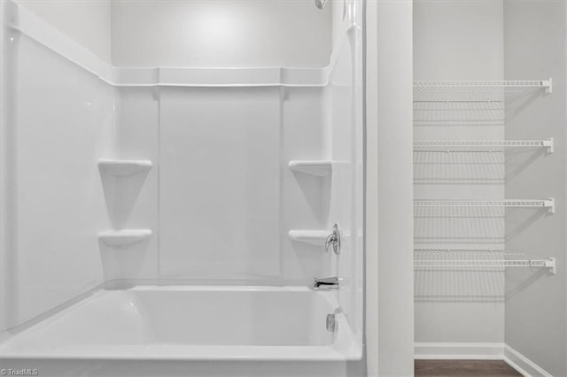 bathroom with wood-type flooring and washtub / shower combination