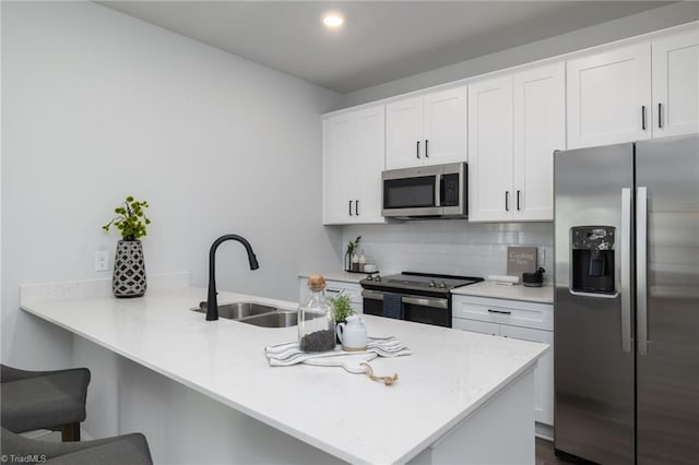 kitchen with white cabinets, kitchen peninsula, appliances with stainless steel finishes, and sink