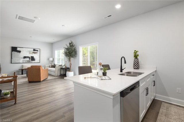 kitchen with light hardwood / wood-style floors, sink, kitchen peninsula, stainless steel dishwasher, and white cabinets