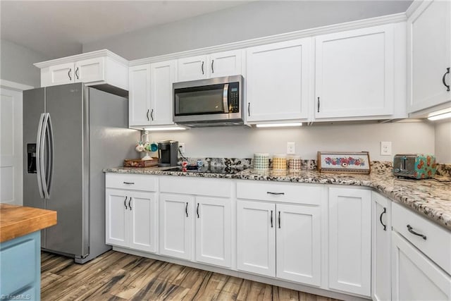 kitchen featuring white cabinets, light stone countertops, light wood-type flooring, and appliances with stainless steel finishes