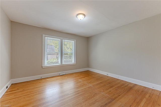 spare room featuring light wood-style flooring, visible vents, and baseboards