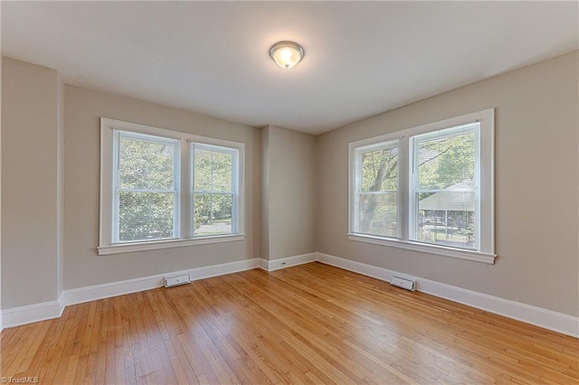 unfurnished room featuring baseboards, light wood-style floors, and visible vents