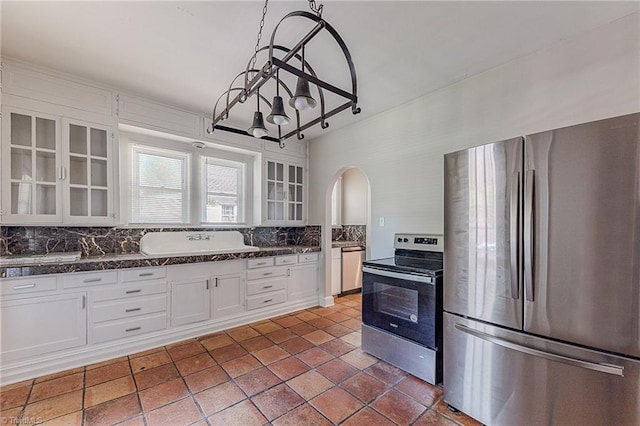 kitchen featuring backsplash, arched walkways, stainless steel appliances, and white cabinets
