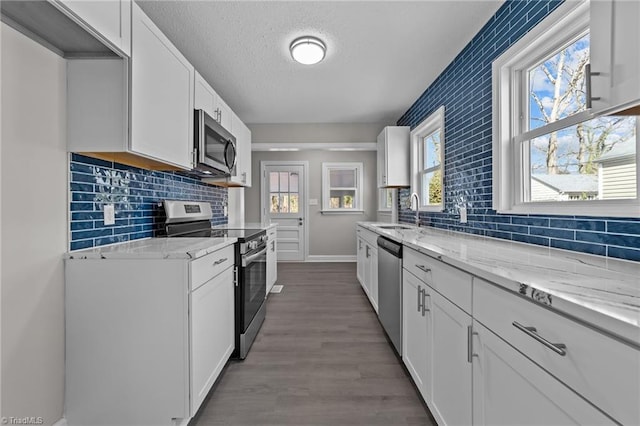 kitchen featuring white cabinets, light stone countertops, and stainless steel appliances