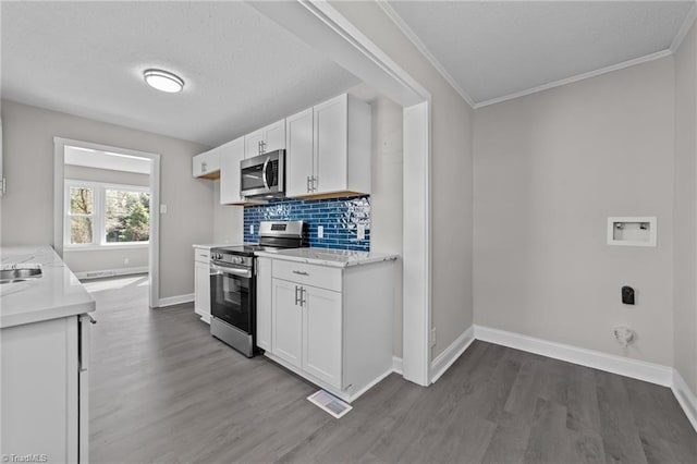 kitchen featuring backsplash, appliances with stainless steel finishes, white cabinets, and wood finished floors