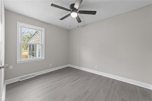 empty room featuring visible vents, dark wood finished floors, a textured ceiling, and baseboards