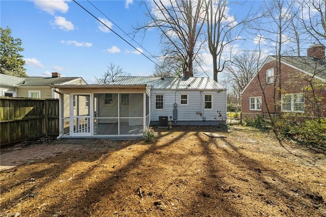 rear view of house featuring a sunroom, a fenced backyard, metal roof, and central AC unit