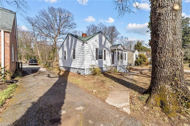 view of side of home with aphalt driveway and a chimney