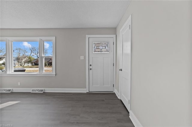 entrance foyer with baseboards, a textured ceiling, visible vents, and dark wood-type flooring