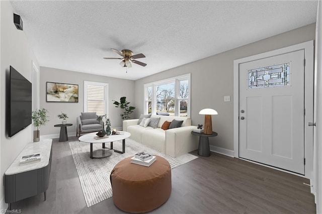 living room featuring ceiling fan, a textured ceiling, baseboards, and wood finished floors